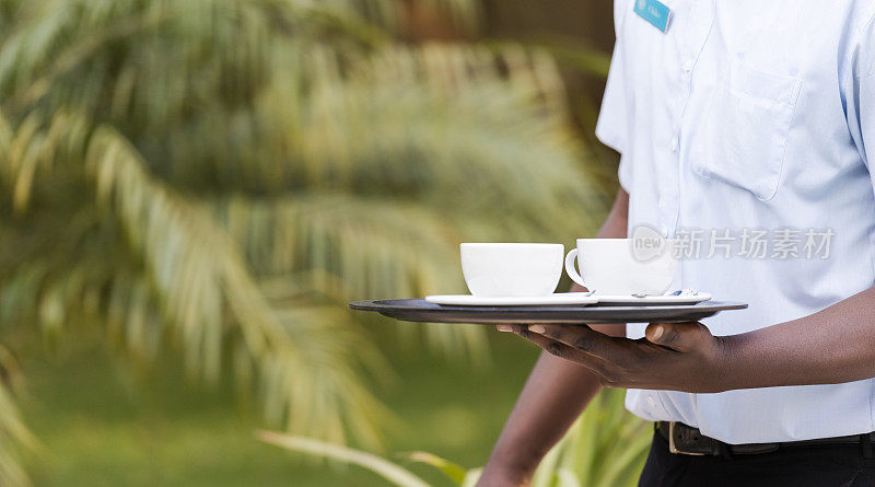 Close up waiter carrying coffee cups on tray